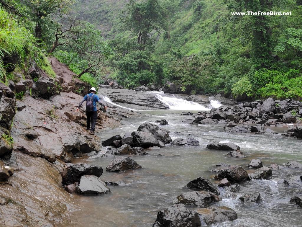 Walking by the Kalu river to reach bottom of Kalu waterfall in Gods valley